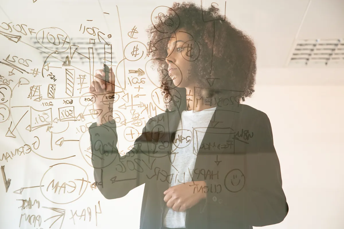 A strategist mapping ideas across a glass surface